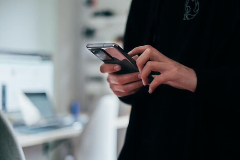 Close-up of a person holding and typing on a modern smartphone