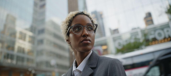 Professional wearing round Dymesty camera-free AI glasses while walking through a modern city